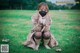 A woman wearing a face mask sitting on the grass.