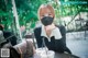 A woman sitting at a table wearing a face mask.