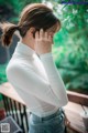 A woman in a white shirt is holding her head in her hands.