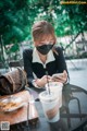 A woman sitting at a table with a cup of coffee and a cell phone.