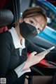 A woman wearing a face mask while sitting in a car.