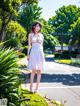 A woman in a white dress standing on the side of a road.