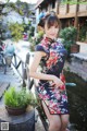 A woman in a black and red floral dress posing for a picture.