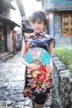 A woman in a black dress holding a blue fan.