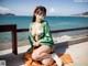 A woman in a green and orange kimono sitting on the beach.