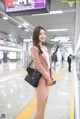 A woman in a pink suit standing in a subway station.